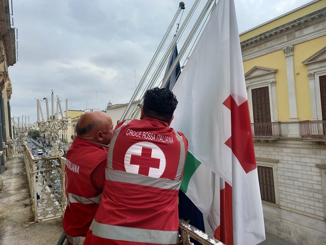 La bandiera della Croce Rossa Italiana esposta sulla facciata di Palazzo Gentile per la Giornata mondiale